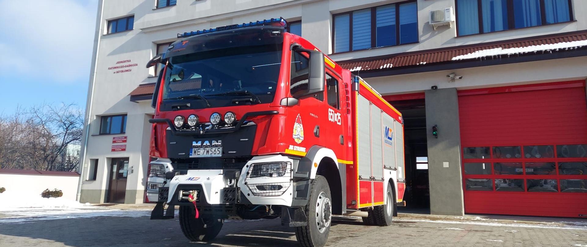 Zdjęcie przedstawiające nowo zakupiony ciężki samochód ratowniczo-gaśniczy na tle Komendy Powiatowej Państwowej Straży Pożarnej w Szydłowcu