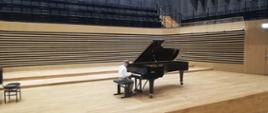 Uczeń grający na fortepianie na scenie sali koncertowej PSM