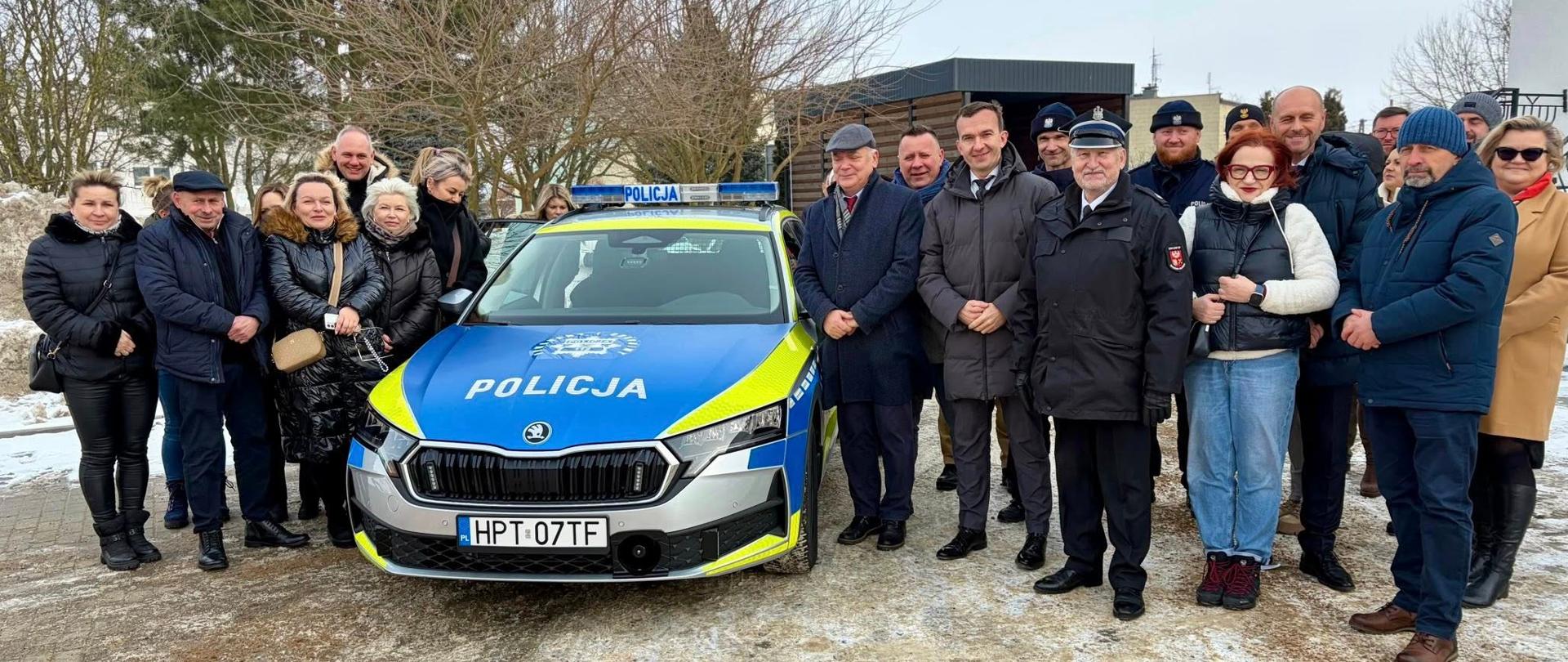 Nowe inwestycje w Zalewie: uczestnicy wydarzenia, kilkanaście osób, przy nowym samochodzie policyjnym.
