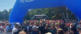 Zdjęcie przedstawia uczestników i osoby kibicujące podczas Mistrzostw Służb Mundurowych i Paramundurowych w ramach Garmin Triathlon Tour Rawa Mazowiecka 2026, w tle baner z napisem aqua speed
