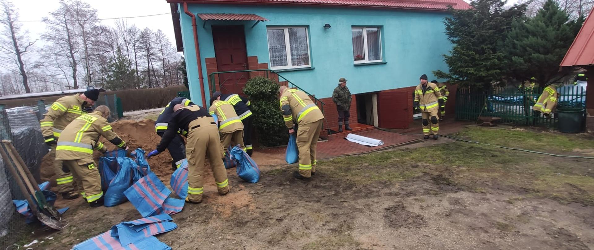 Strażacy sypią piasek do worków na budową wału przeciwpowodziowego