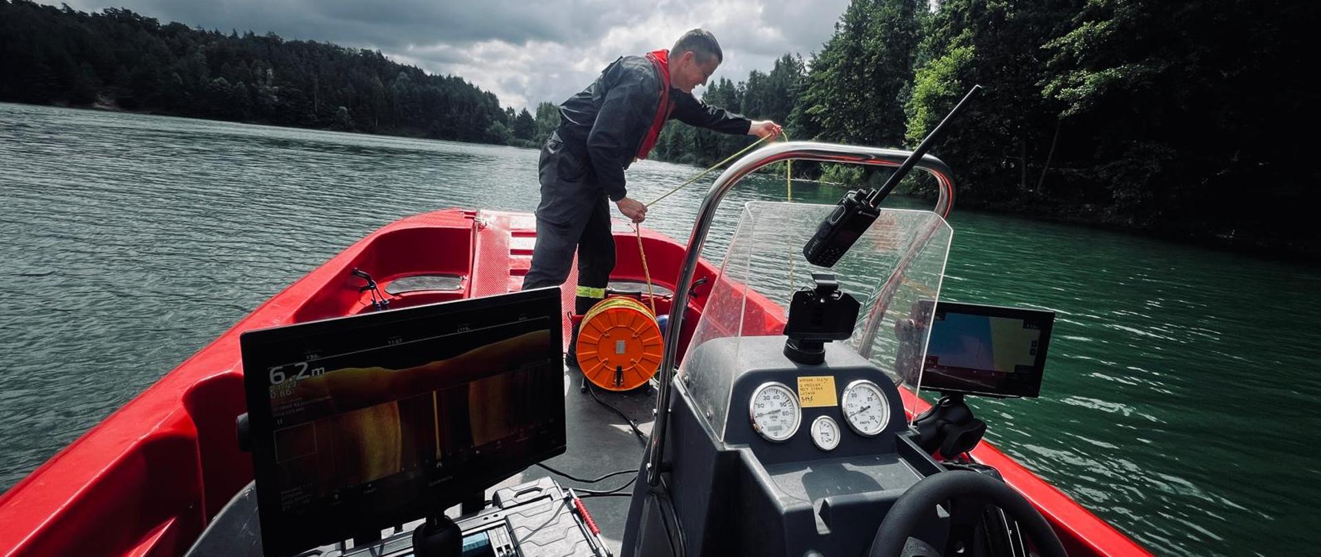 strażak na łodzi ratowniczej trzymający w rękach linę