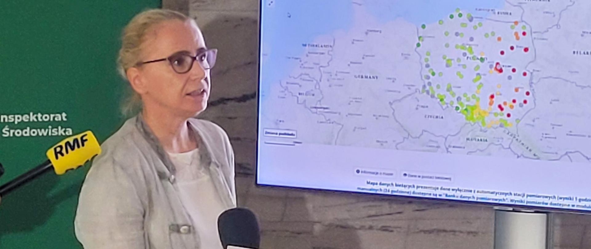 Kobieta przed mikrofonem obok mapy polski