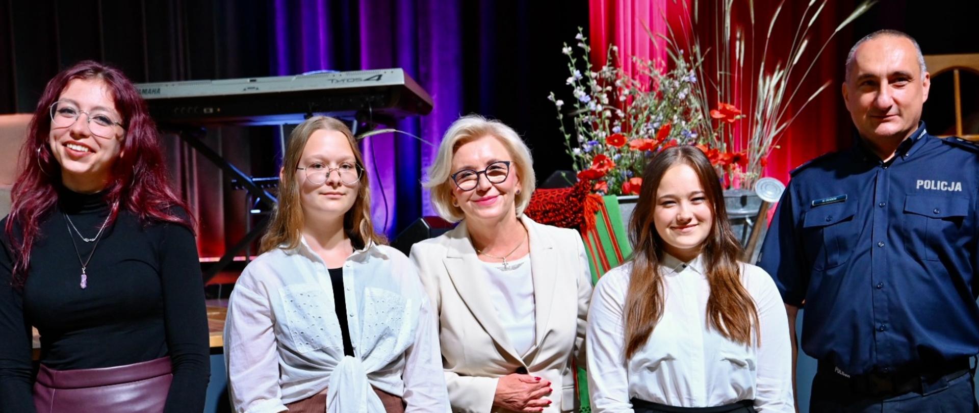 Wiceminister Machałek stoi pośrodku grupy pięciu osób, obok niej trzy kobiety i policjant.