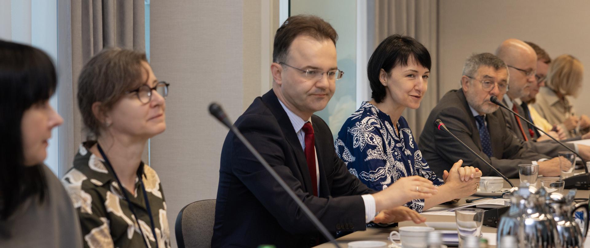 Dyrektor generalna siedząca przy stole z innymi uczestnikami narady.