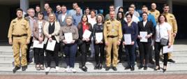 Grupowe zdjęcie uczestników szkolenia (25 osób) w towarzystwie Komendanta oraz Zastępcy Komendanta Centralnej Szkoły PSP oraz dwóch funkcjonariuszy CS PSP