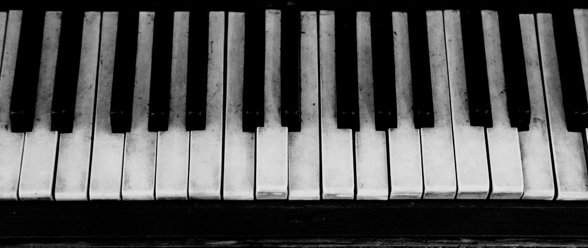 Zdjęcie przedstawia klawiaturę ze starego fortepianu. Jest ona zniszczona, klawisze niewypoziomowane, brudne.