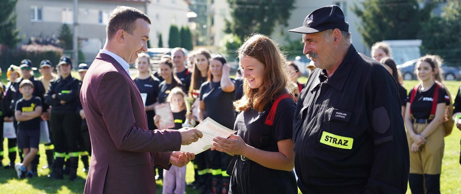 Mężczyzna wręcza dziewczynce dyplom 