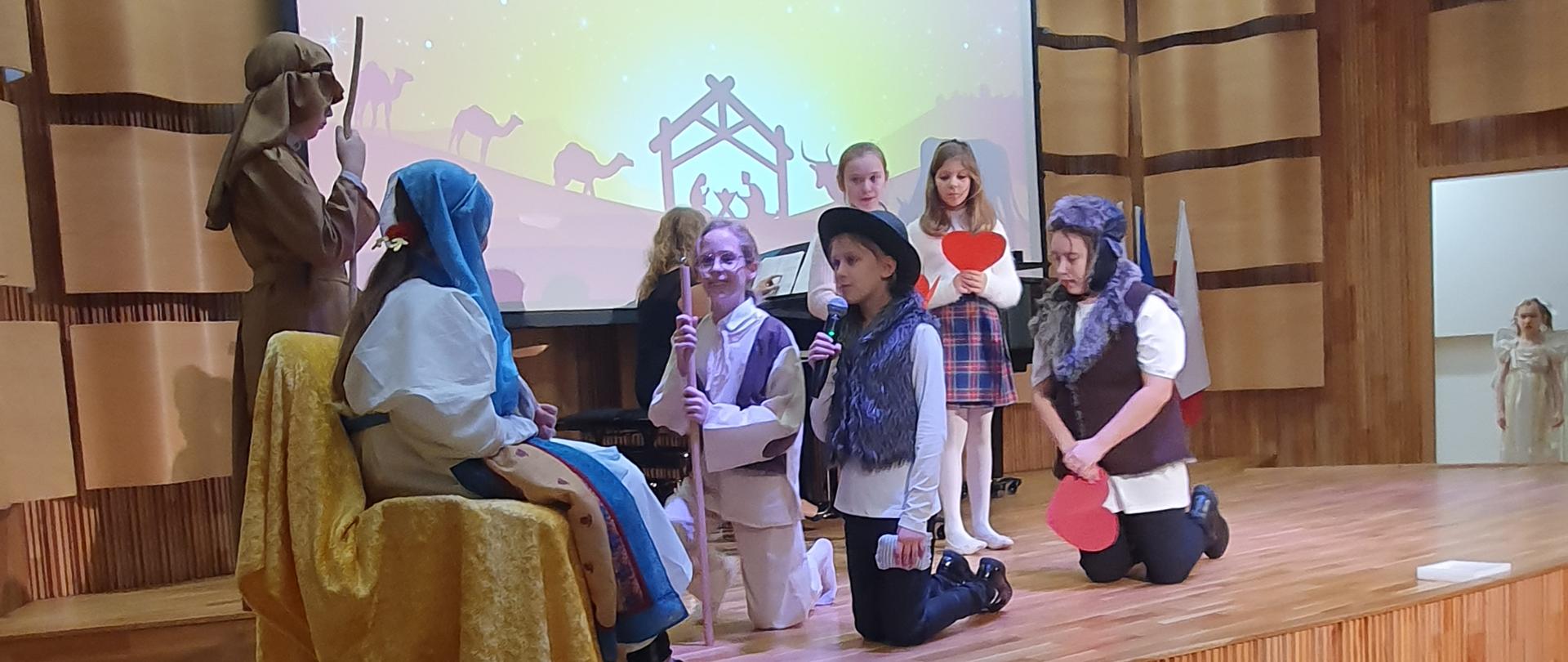 Zdjęcie jasełek. Na scenie sali koncertowej dzieci przebrane na postaci z biblii. 