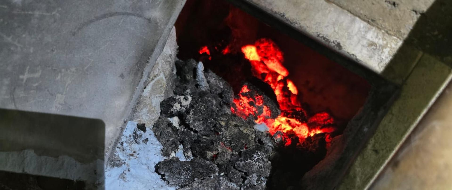 Na zdjęciu widoczna jest wyczystka przewodu kominowego, wewnątrz której znajduje się rozżarzona sadza.