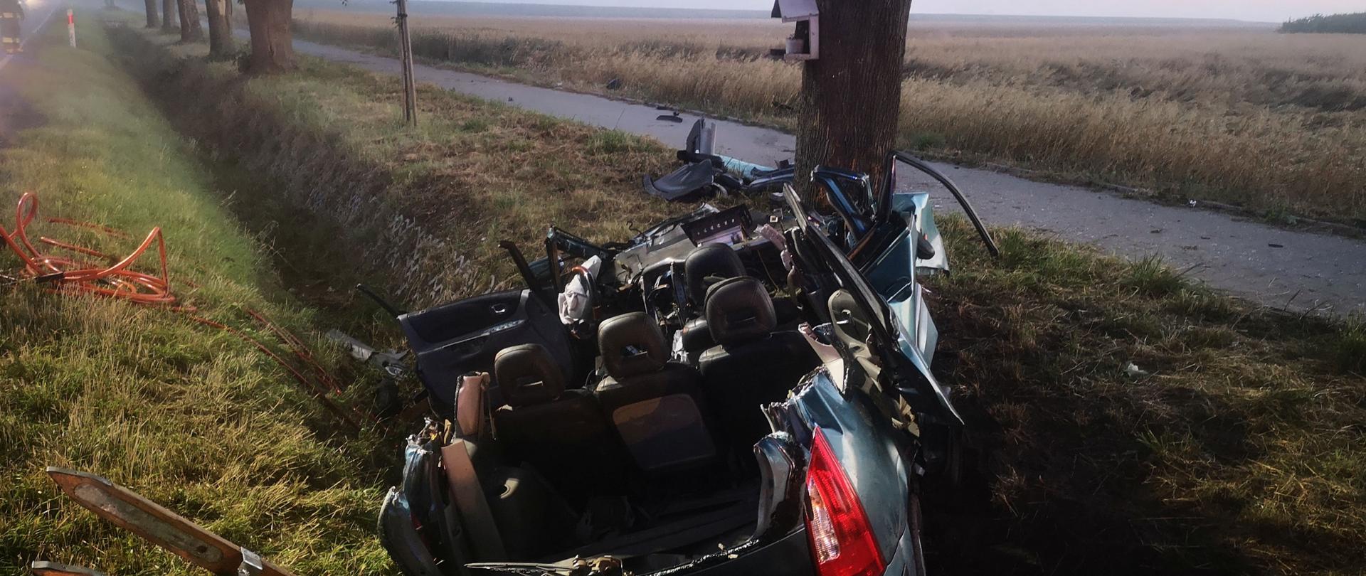 Widok rozbitego pojazdu znajdującego się w rowie po zakończonej akcji. W pojeździe usunięto dach celem ewakuacji kierowcy. O głębokości rowu świadczy drabina, która została sprawiona na krawędzi celem bezpiecznego zejścia. Na poboczu widać węże hydrauliczne służące do zasilania narzędzi. Robi się jasno, wstaje nowy dzień.