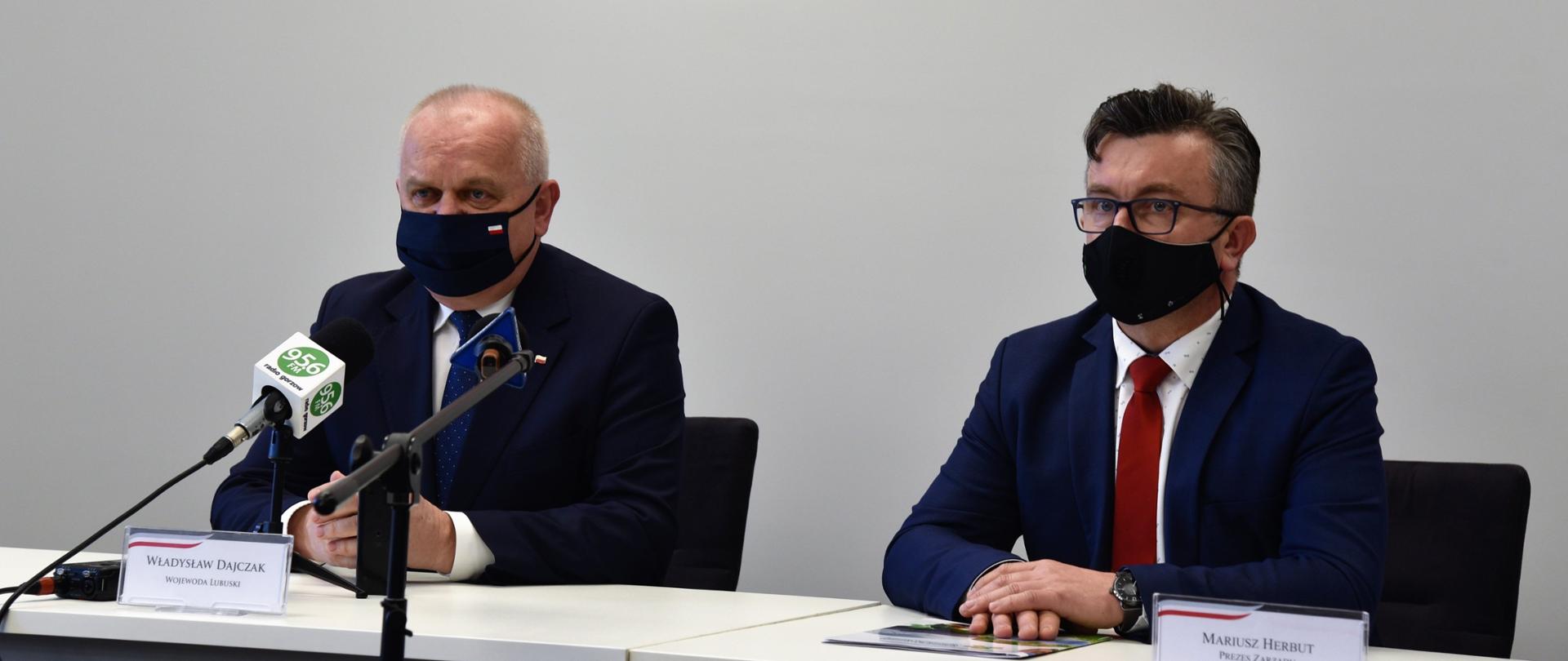 Wojewoda Lubuski Władysław Dajczak siedzi przy stole konferencyjnym z prezesem zarządu Wojewódzkiego Funduszu Ochrony Środowiska Mariuszem Herbutem. Przed nimi stoją mikrofony oraz wizytówki z nazwiskami. 