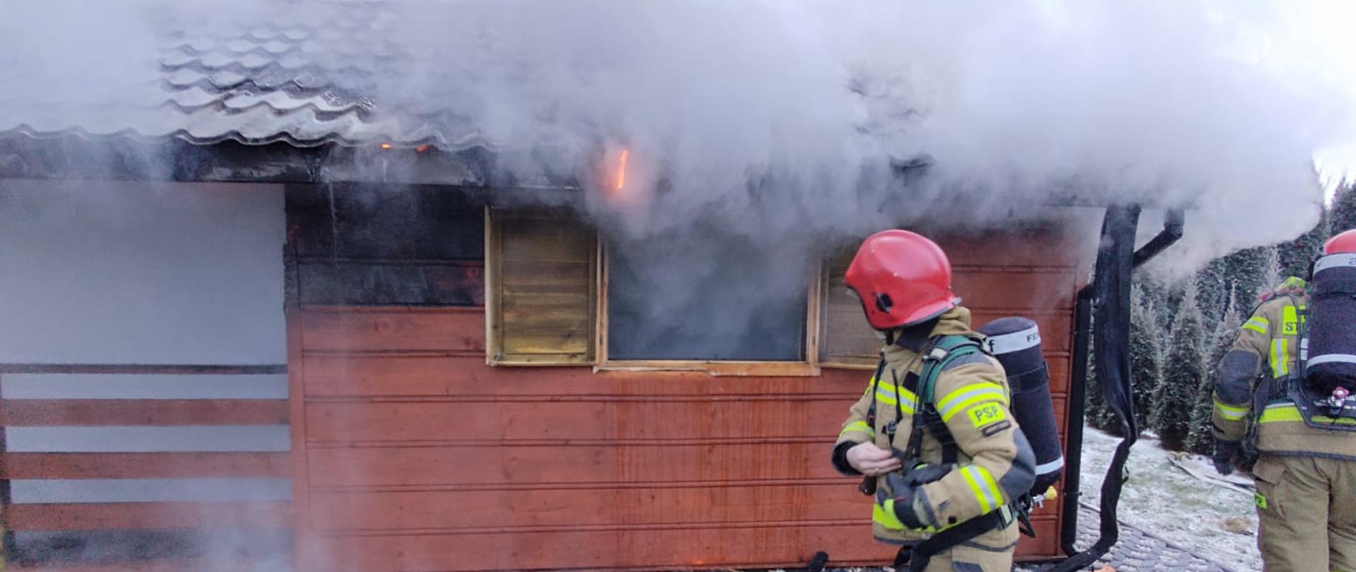 Strażacy gaszą pożar domku letniskowego.