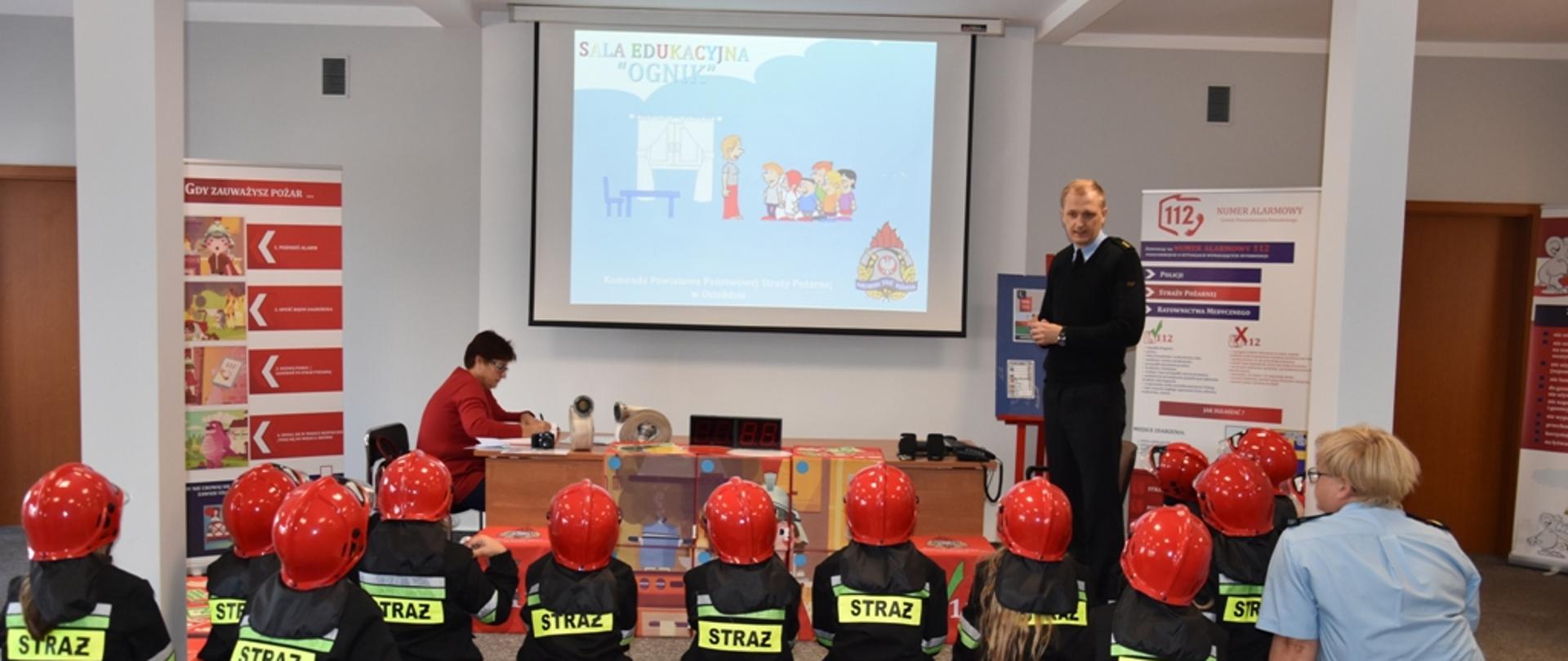 Dzieci siedzą i wysłuchują prelekcji w sali edukacyjnej "Ognik"