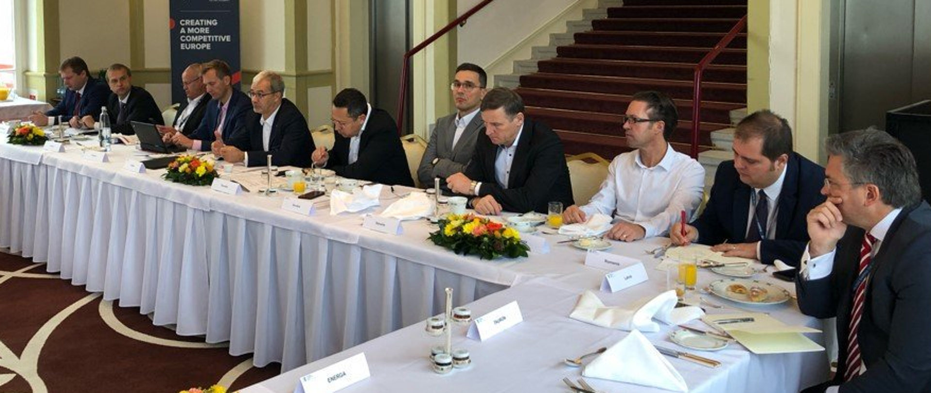 W sali przy stole w kształcie litery L przykrytym białym obrusem siedzą mężczyźni. Wśród nich minister Jerzy Kwieciński.