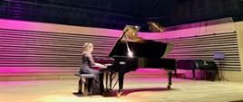 Młoda kobieta gra na fortepianie na scenie sali koncertowej PSM w Jastrzębiu-Zdroju