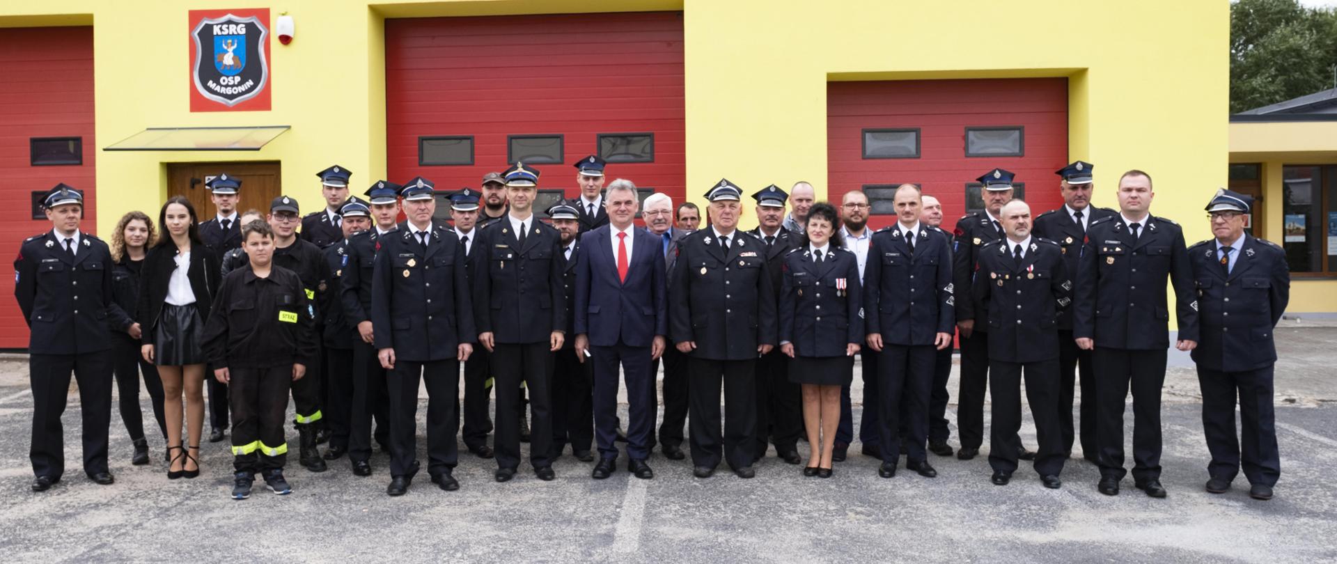 Zdjęcie przedstawia strażaków i samorządowców uczestniczących w zebraniu sprawozdawczo-wyborczym w remizie OSP Margonin.
W tle budynek jednostki OSP Margonin.
