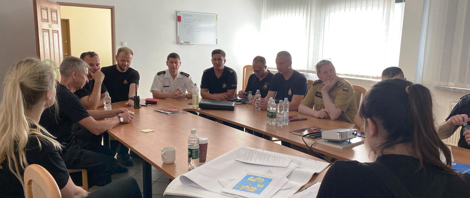 Uczestnicy warsztatów siedzą wokół owalnego stołu.