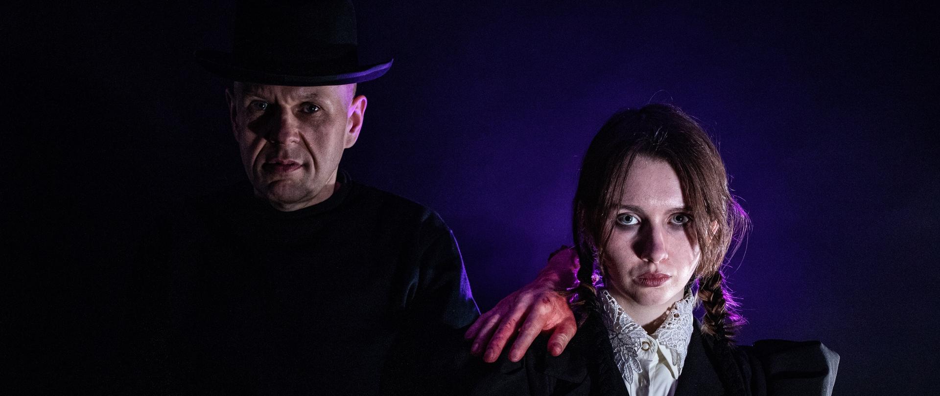 Zdjęcie przedstawia filmową i serialową postać z filmu "Wednesday" oraz "Rodzina Adamsów" - Wednesday Adams w towarzystwie swojego wujka Festera Adamsa. Dziewczyna ma na ramieniu odciętą rękę - manekin. Z tyłu postaci jest delikatnie fioletowe tło. 