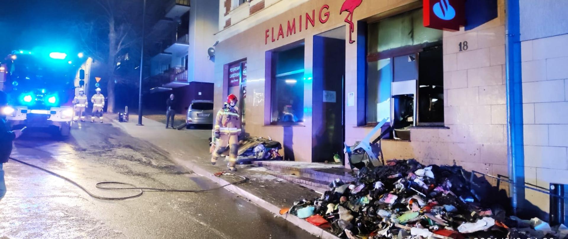  Na zdjęciu strażacy przed budynkiem, gdzie doszło do pożaru