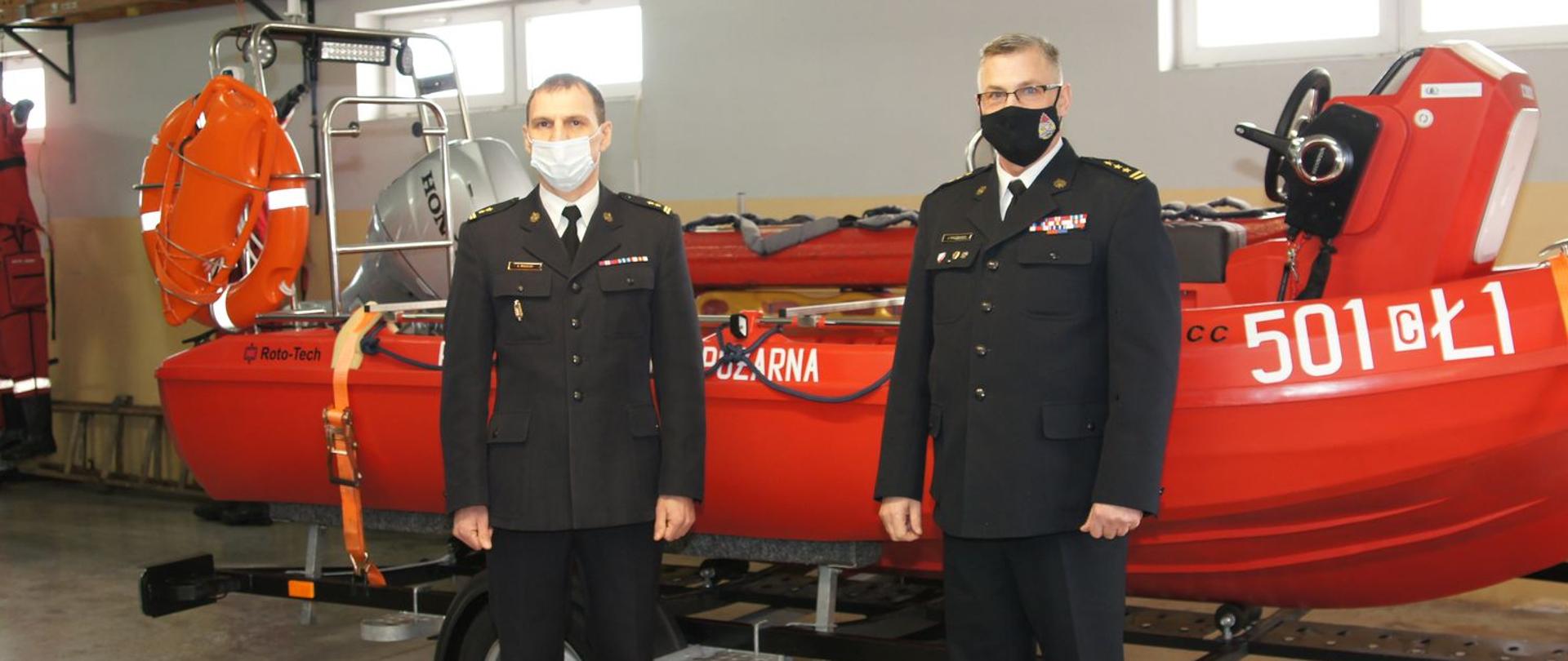 Na zdjęciu, które zostało zrobione w garażu Komendy Powiatowej PSP w Radziejowie widoczna jest czerwona łódź stojąca na przyczepce przystosowanej do przewozu łodzi. Obok łodzi stoi Kujawsko-Pomorski Komendant Wojewódzki PSP w Toruniu i Komendant Powiatowy PSP w Radziejowie 