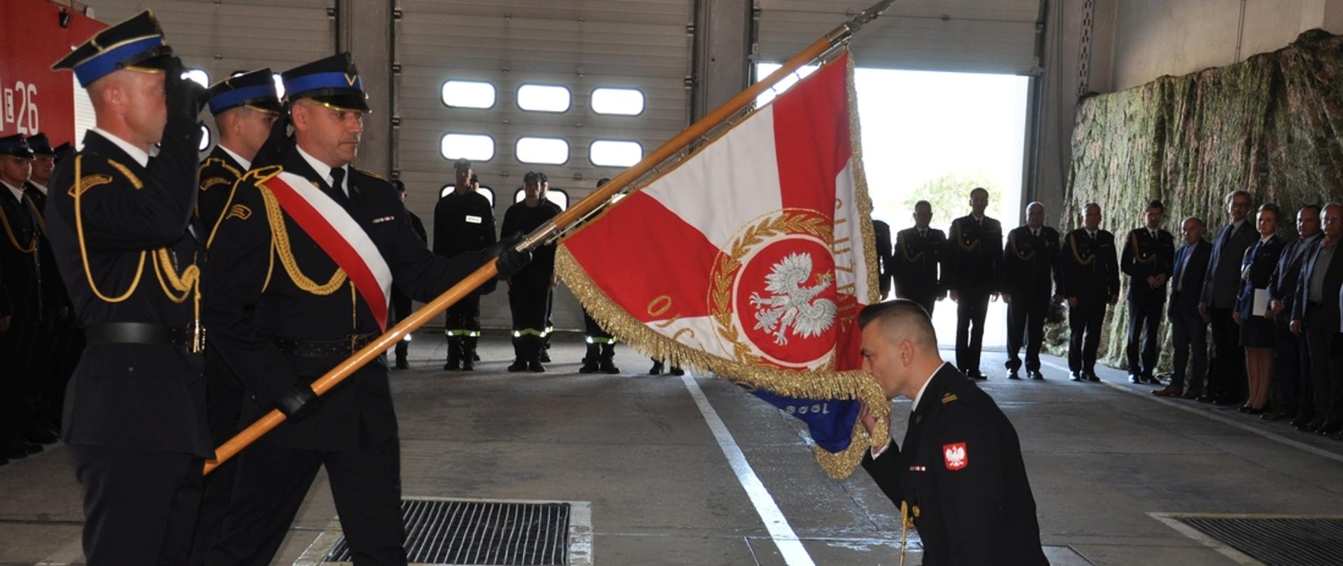 Nowy Komendant oddaje honor poprzez ucałowanie sztandaru w tle zgromadzeni goście