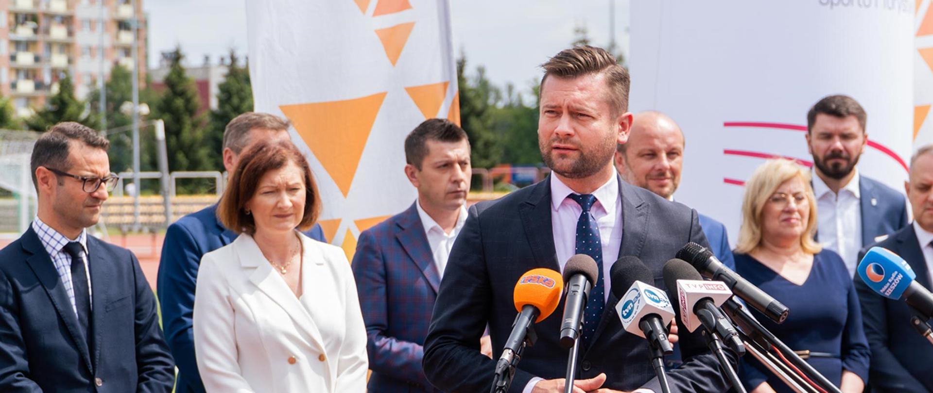 Konferencja prasowa z udziałem ministra Kamila Bortniczuka: podpisanie umowy na dofinansowanie i wsparcie budowy Podkarpackiego Centrum Lekkiej Atletyki. Stadion Resovii Rzeszów, 28.07.2022 r. Przemawia minister Kamil Bortniczuk, w tle goście konferencji.