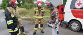 Zatrzymany kierowca w asyście strażaków i ratownika PCK zapoznaje się ze sprzętem ratownictwa technicznego