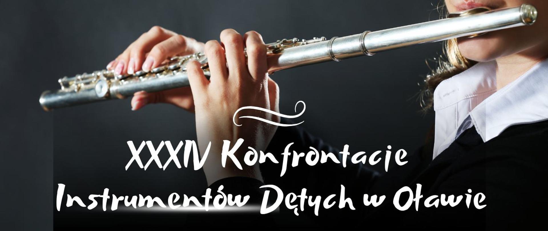 Baner przedstawia flet poprzeczny trzymany w dłoniach kobiety przykładającej go do ust. Pod nim białe ozdobne napisy a wszystko to na czarnym tle.