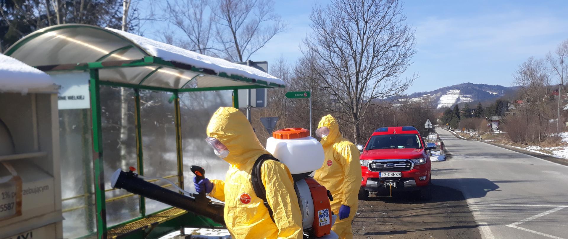 Strażacy w ubraniach ochronnych dezynfekuj przestanek autobusowy
