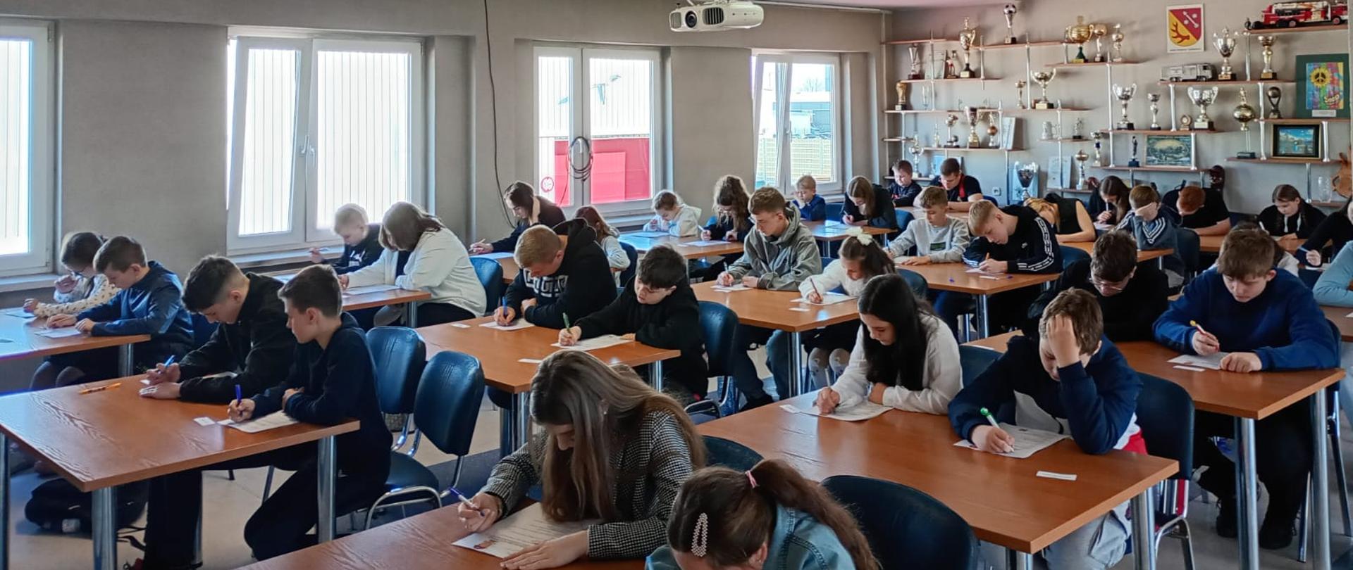 Powiatowe eliminacje Ogólnopolskiego Turnieju Wiedzy Pożarniczej w Żarach, uczestnicy piszą test.