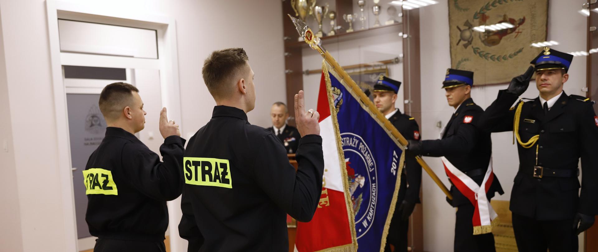 Zdjęcie przedstawia funkcjonariuszy w trakcie składania ślubowania. Na drugim planie salutuje poczet sztandarowy.