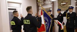 Zdjęcie przedstawia funkcjonariuszy w trakcie składania ślubowania. Na drugim planie salutuje poczet sztandarowy.