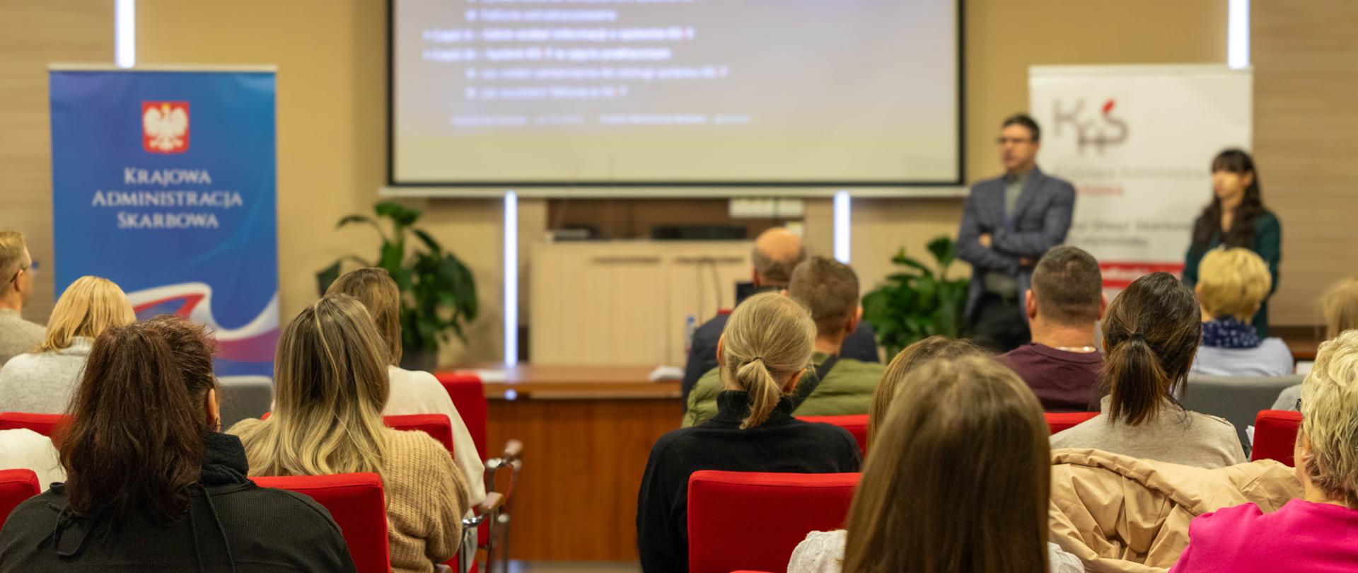 Zebrani na sali patrzą na prezentację