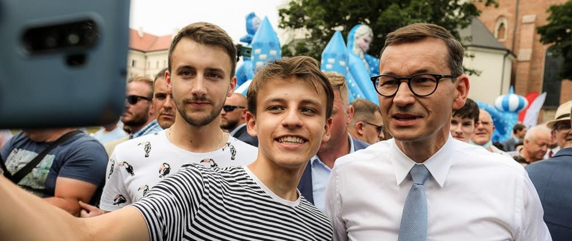 Dwóch młodych mężczyzn robi sobie zdjęcie z premierem.