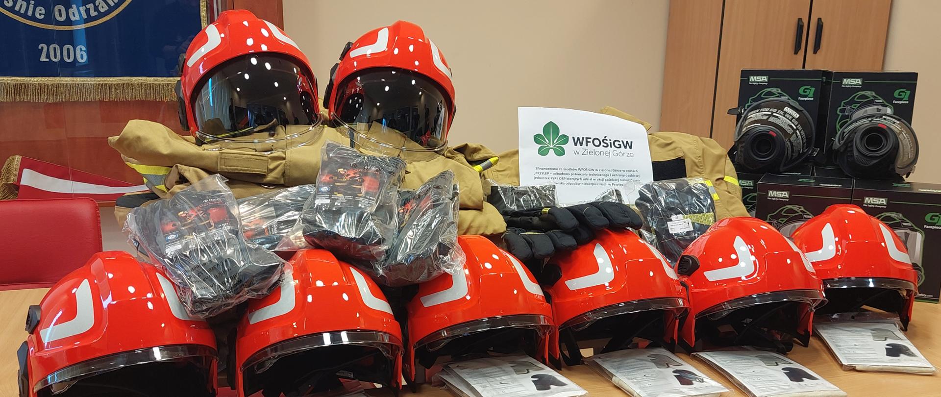 Zdjęcie przedstawia sprzęt do odbudowy potencjału technicznego i ochrony osobistej jednostek PSP. Na zdjęciu widać głównie hełmy strażackie, maski do aparatów powietrznych oraz rękawice specjalne.