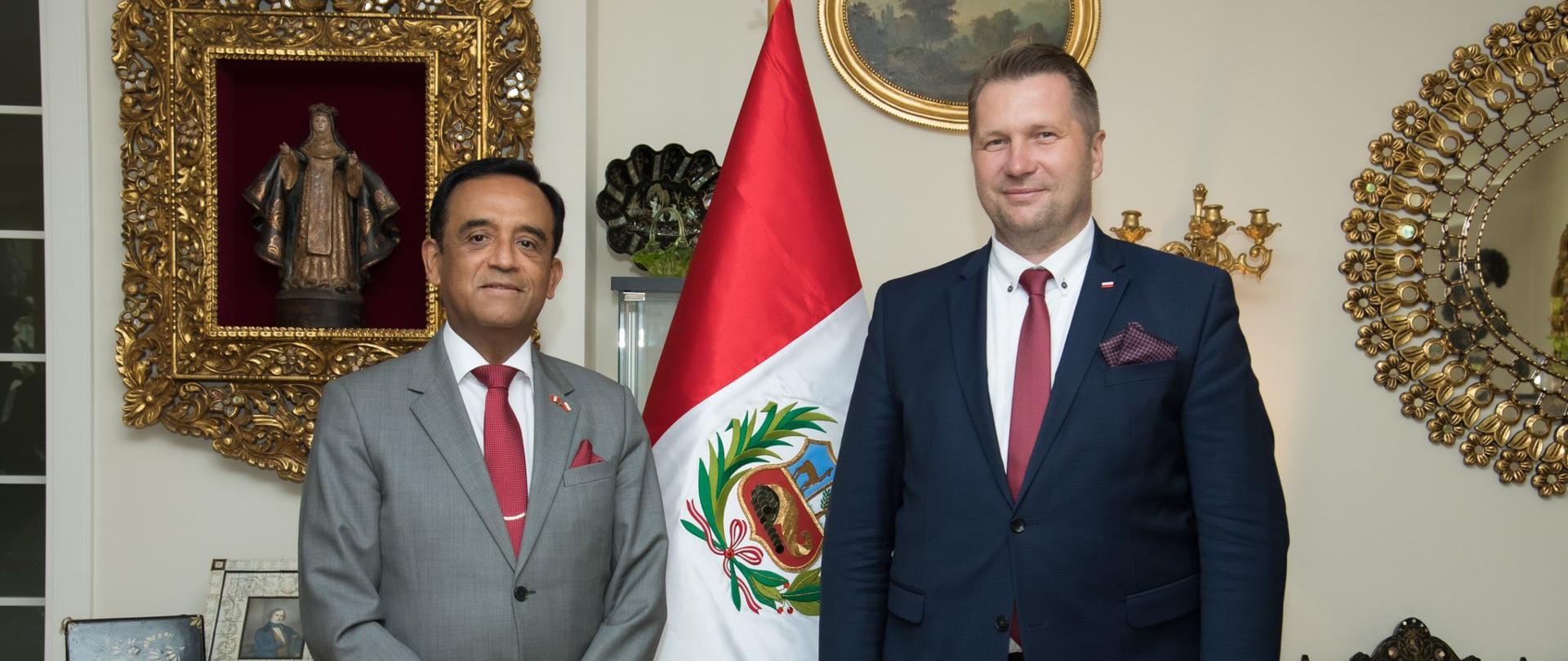 Ambasador Peru w Polsce i Minister Edukacji i Nauki stoją obok siebie w bogato urządzonym pomieszczeniu z flaga Peru w tle.