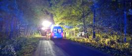 Na zdjęciu pora nocna, droga lokalna biegnąca przez las. Na drodze stoi samochód ZRM, za nim widać strażaków a następnie samochód OSP Łobżenica. Z prawej strony w lesie stoi uszkodzony pojazd.