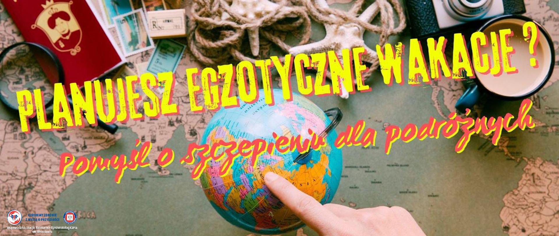 osoba wskazująca palcem na punkt na globusie na tle mapy oraz rozłożonych atrybutów podróżniczych