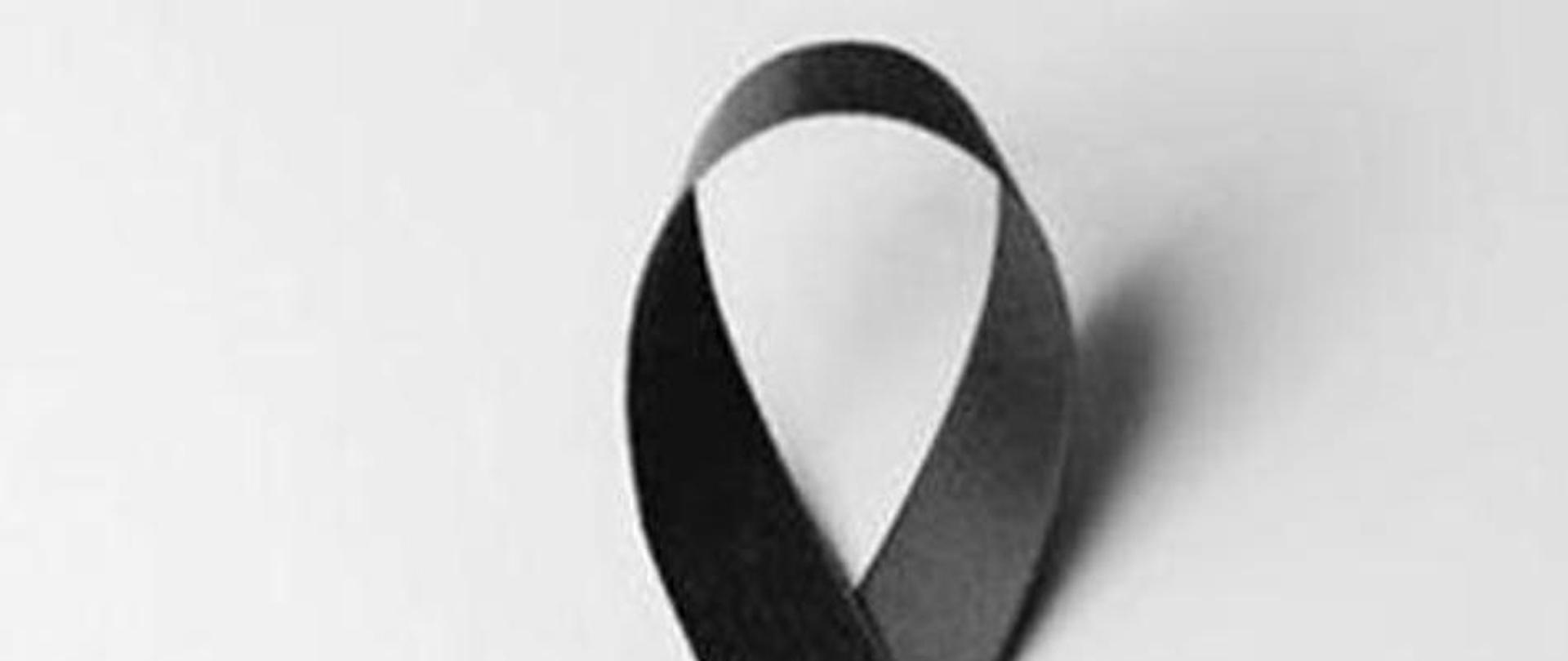 Zdjęcie przedstawia czarną, żałobną wstęgę na białym tle