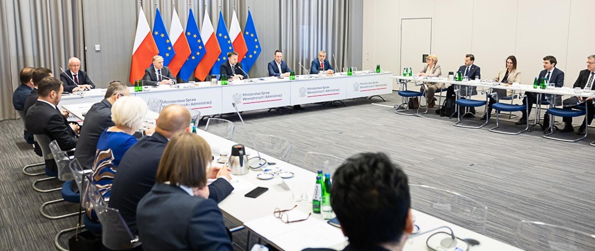 Sala narad z uczestnikami spotkania za stołami konferencyjnymi 