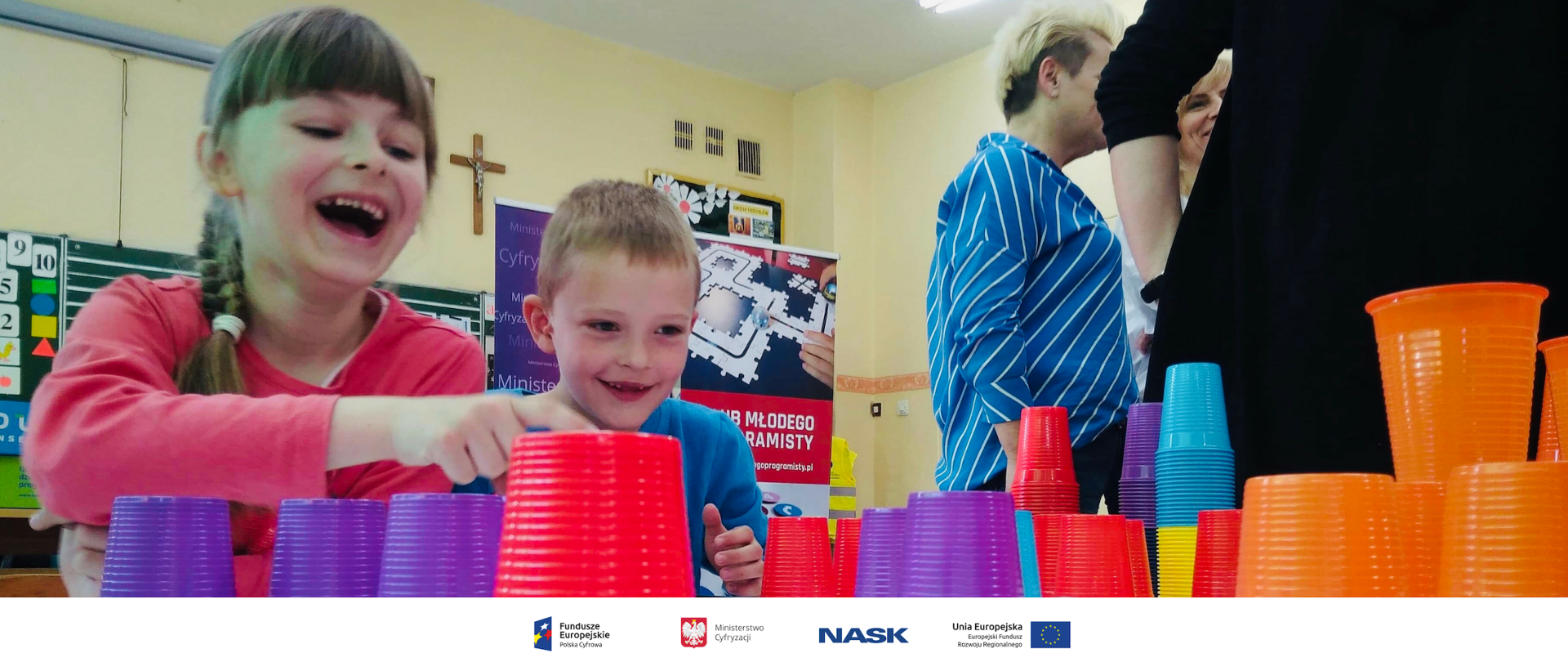 Uśmiechnięte dzieci bawią się kolorowymi kubeczkami