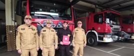 Komendant miejski PSP, zastępca komendanta, dowódca JRG oraz Adrian Petryczko stoją w garażu JRG 1 