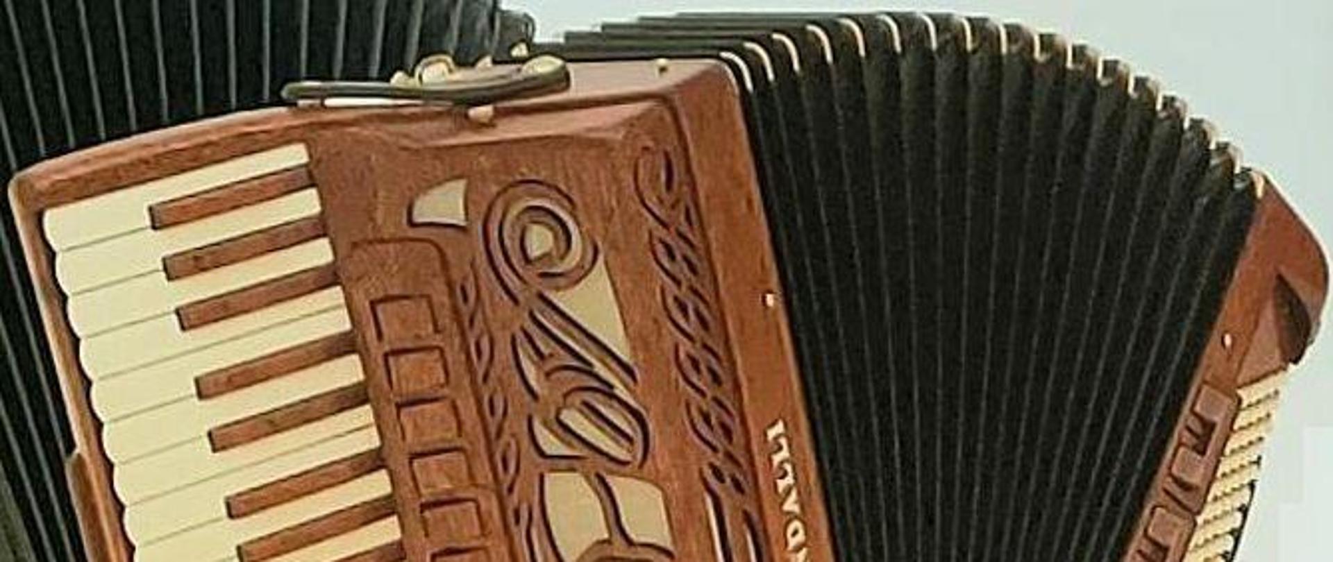 Grafika kolorowa. Akordeon w kolorze brązowym.