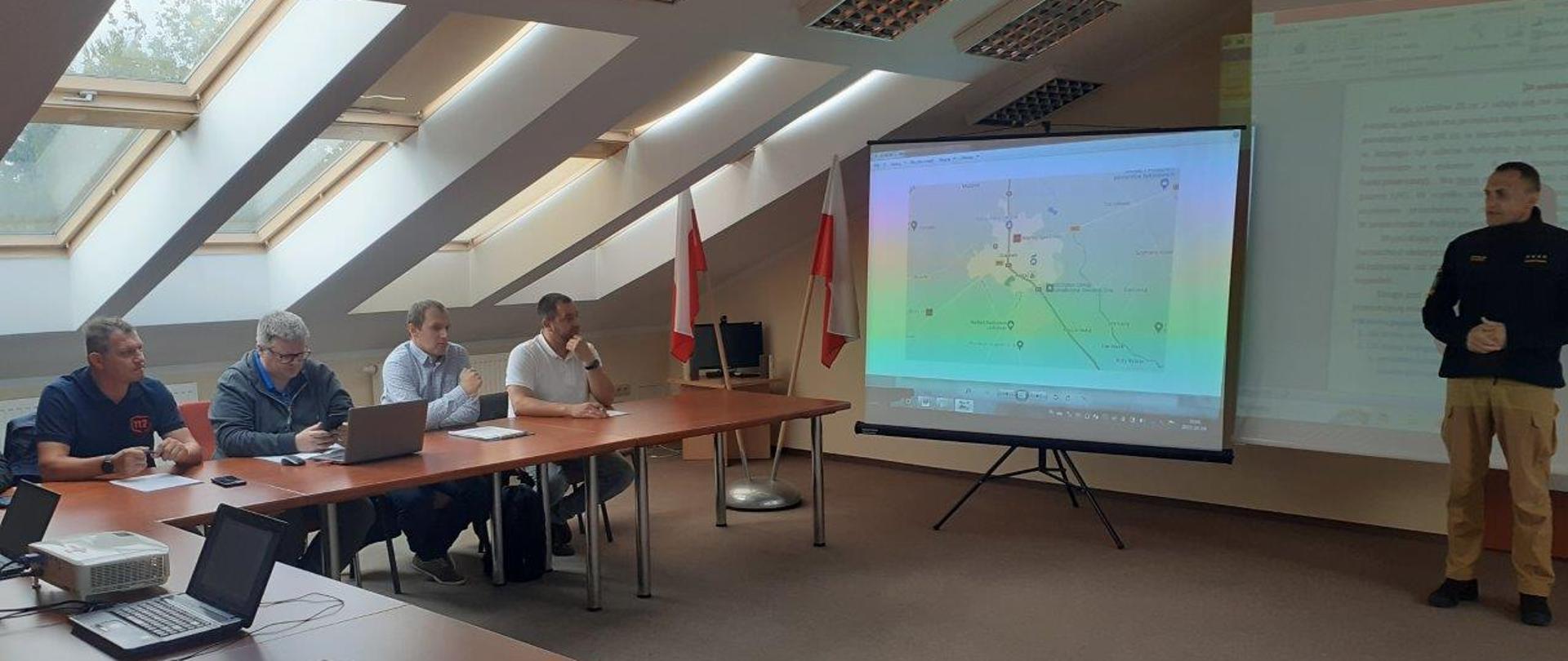 Uczestnicy konferencji siedzą na sali przy stolikach.