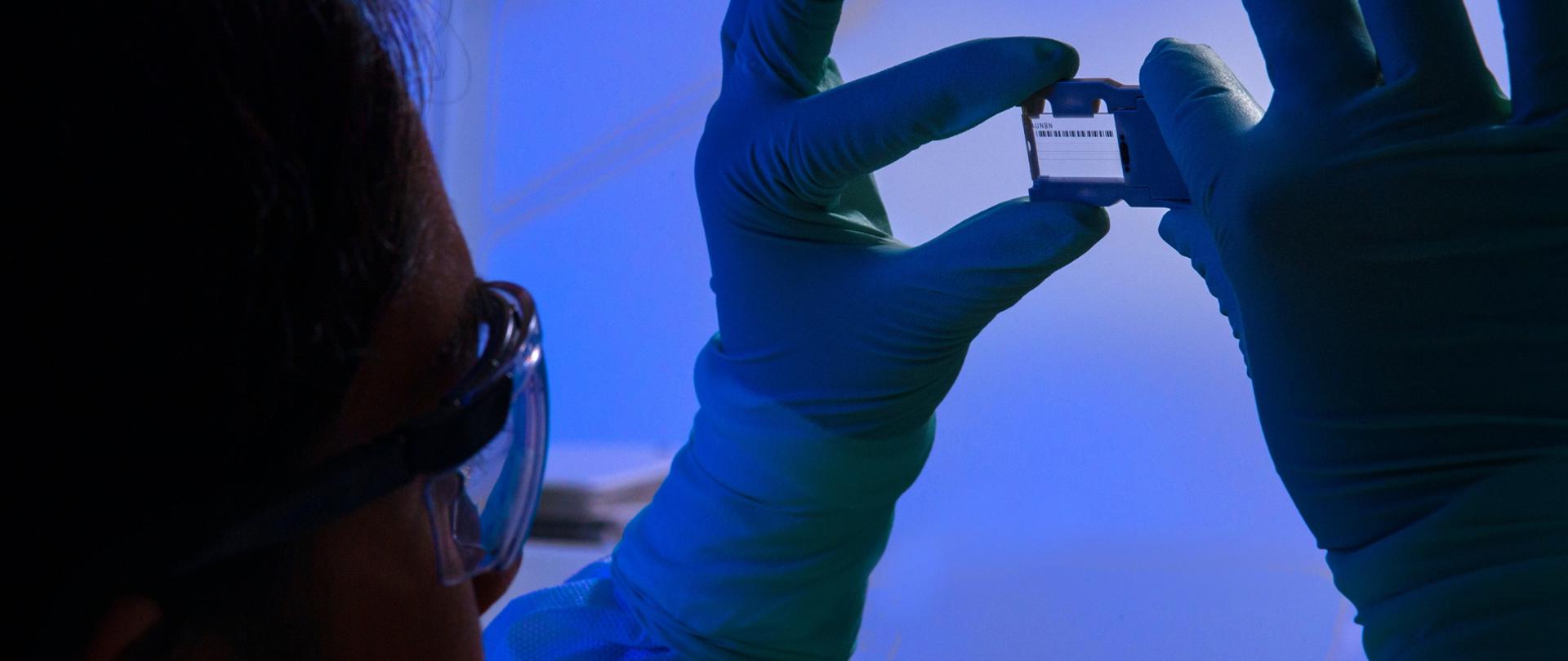 Kobieta w lekarskim fartuchu patrzy przez szkiełko.