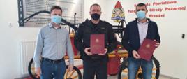 Strażak i dwóch przedstawicieli firmy po podpisaniu umowy
