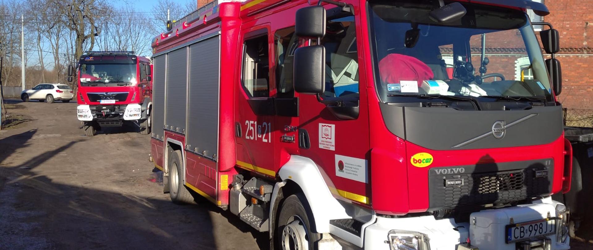 Na pierwszym planie przód pojazdu ratowniczo-gaśniczego na podwoziu Volvo, w tle przód pojazdu samochodu ratowniczo-gaśniczego na podwoziu marki Man. Obydwa pojazdy koloru czerwonego należące do Jednostki Ratowniczo-Gaśniczej Szkoły Podoficerskiej PSP w Bydgoszczy. 