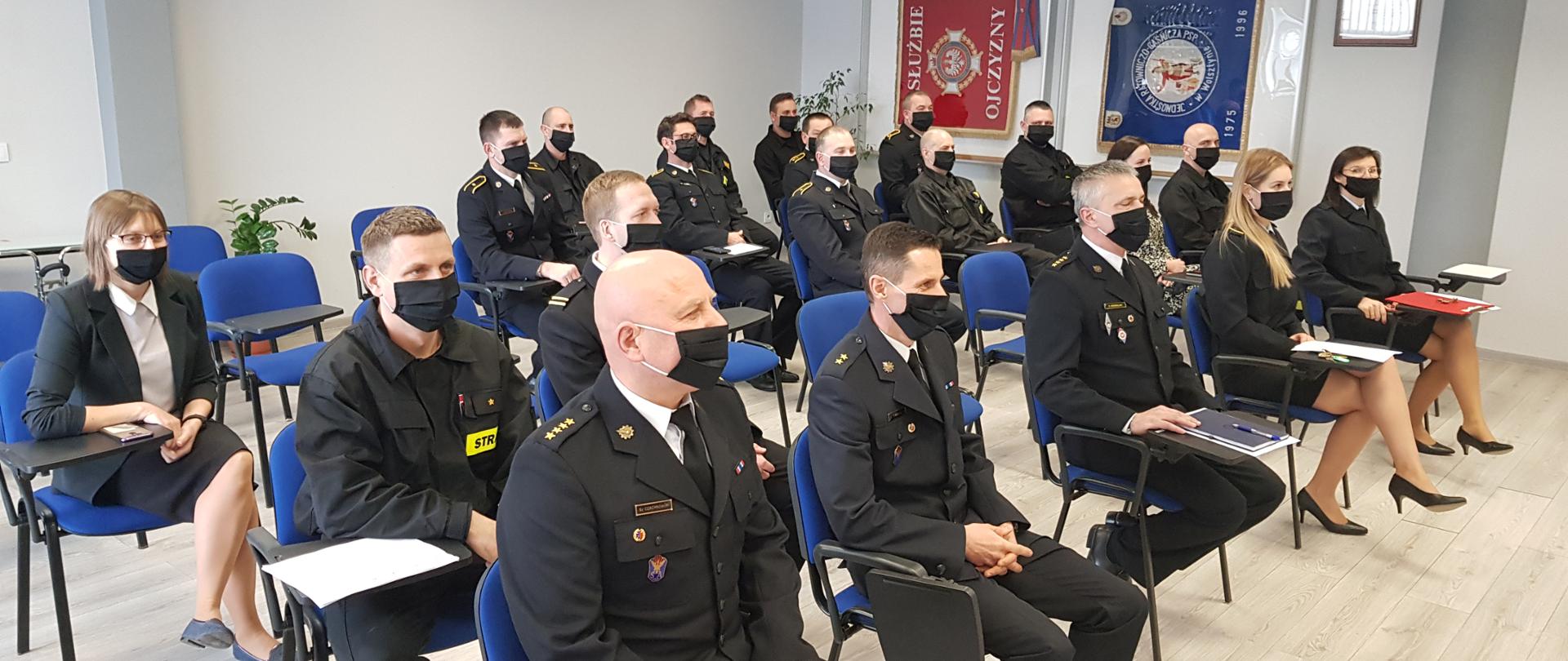 Funkcjonariusze oraz pracownicy cywilni komendy podczas narady. Założone maseczki na twarzach.