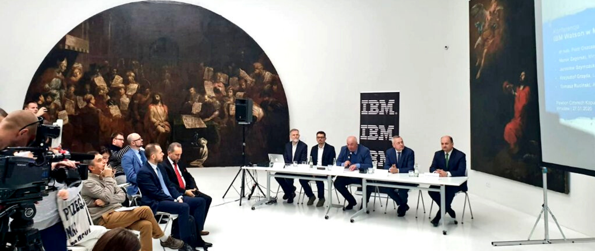 Minister Marek Zagórski siedzi przy stole, obok niego czterech mężczyzn. Naprzeciw dziennikarze. Sala muzealna